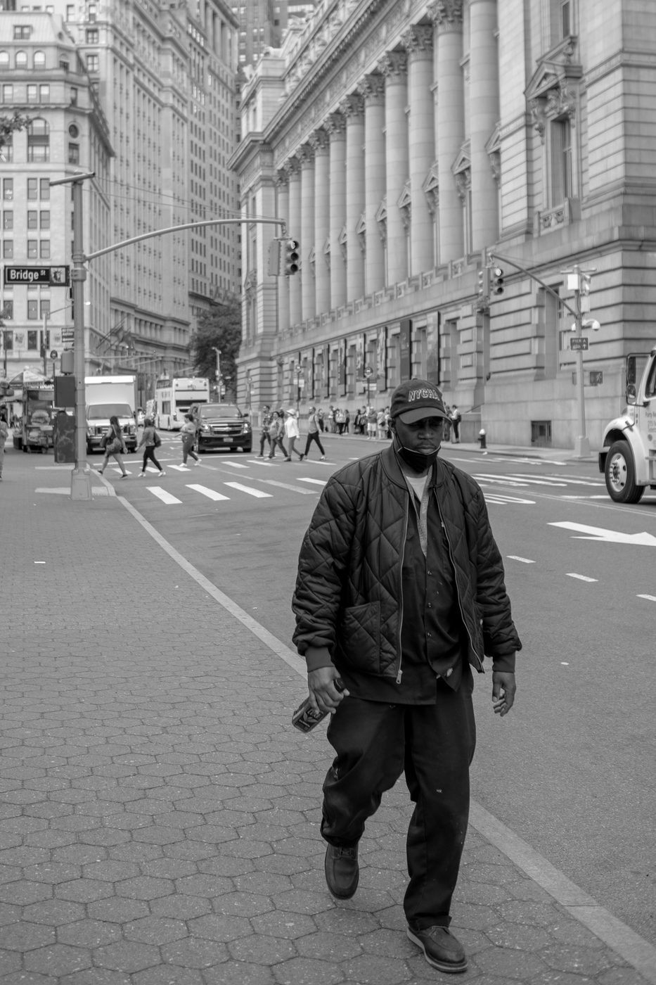 Masked man in a quilted jacket walking past the courthouse columns, New York