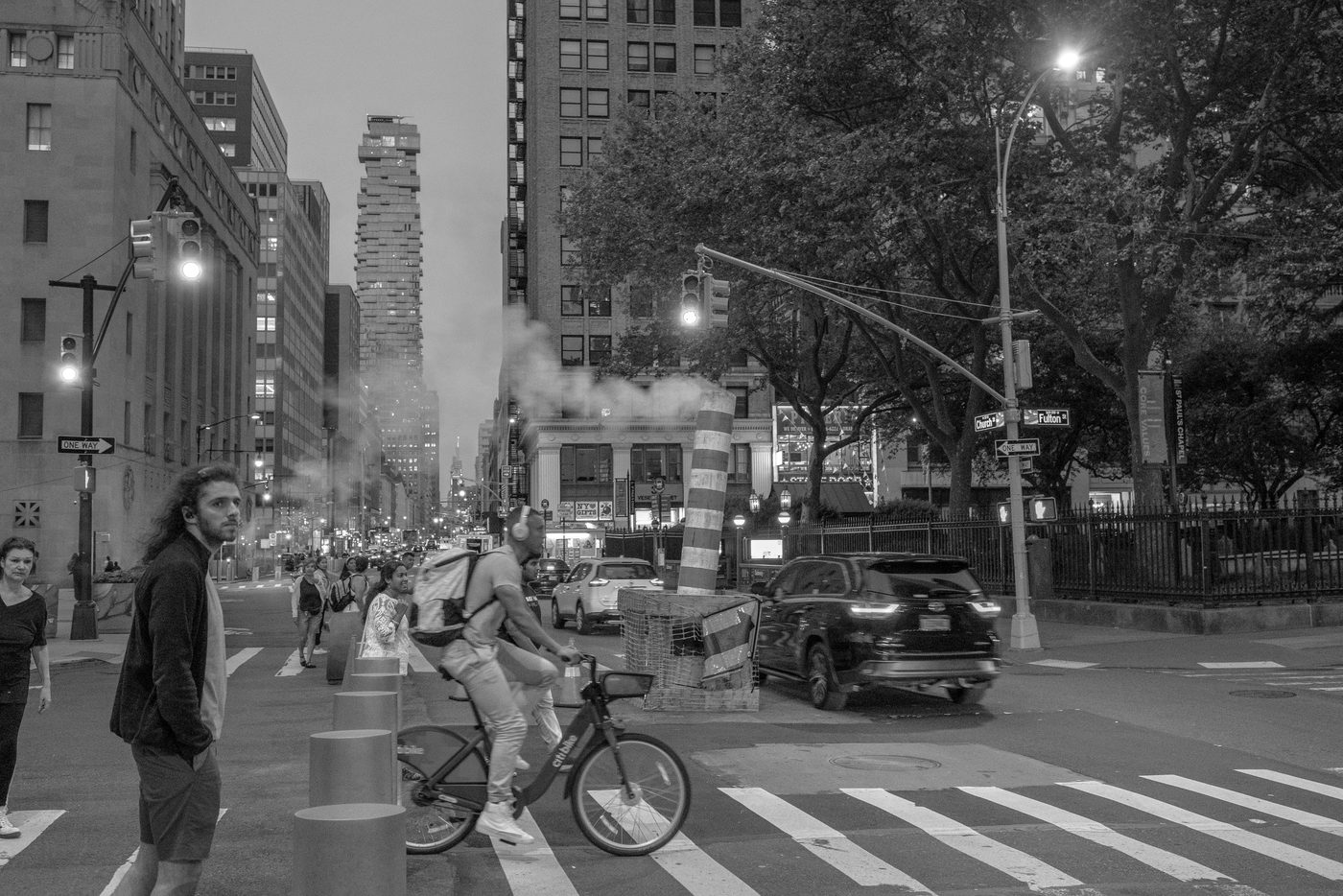 Cyclist on a Citi Bike crossing Church Street at dusk through the steam, New York