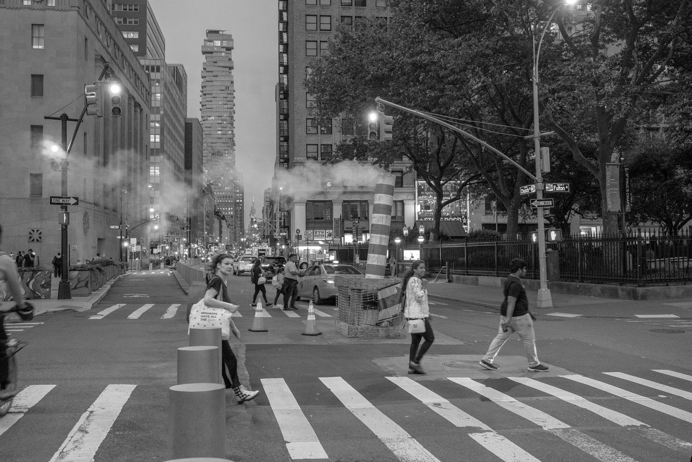 Pedestrians crossing Church Street at dusk near a column of steam, New York