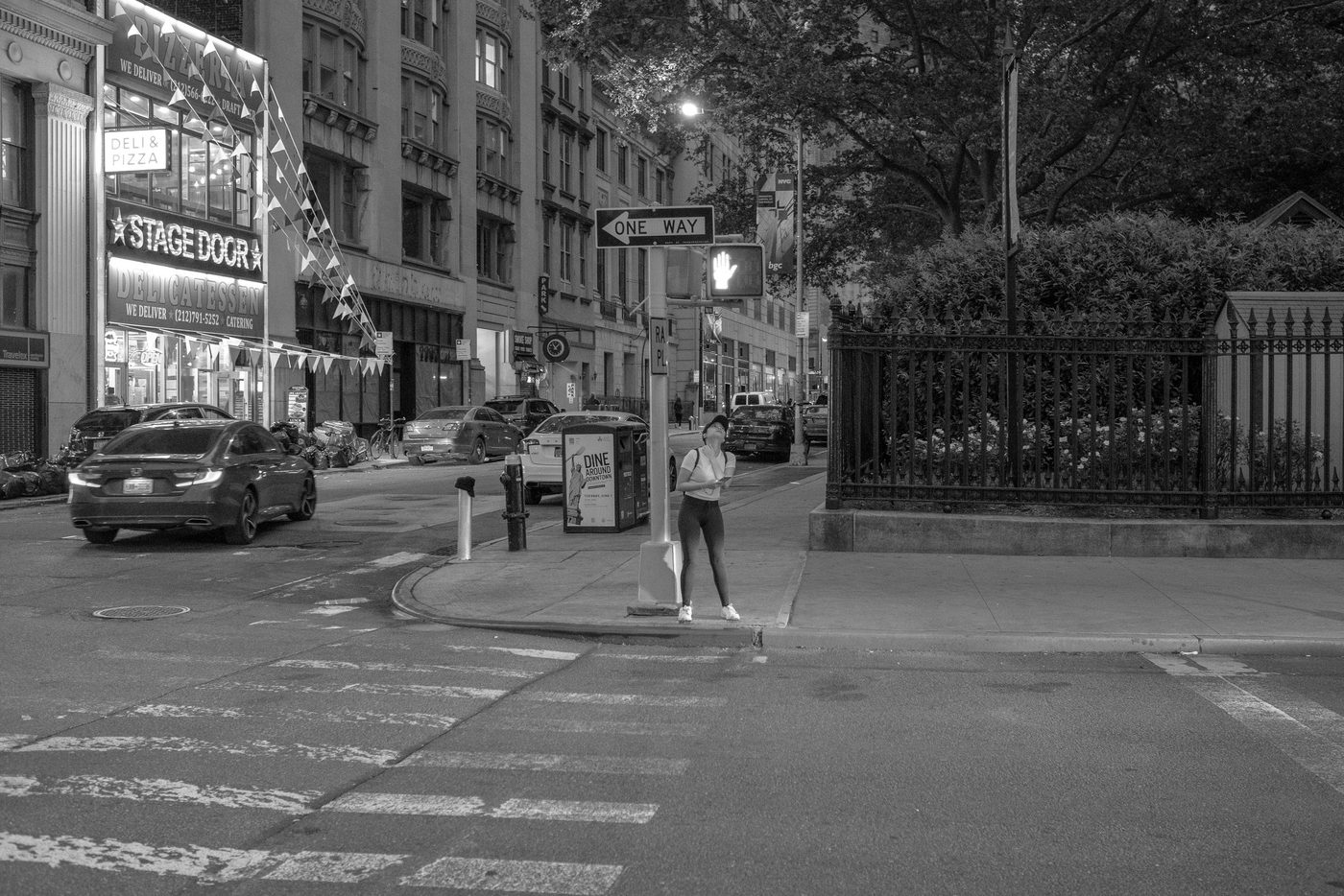 Woman waiting at the light near the Stage Door Delicatessen sign, New York