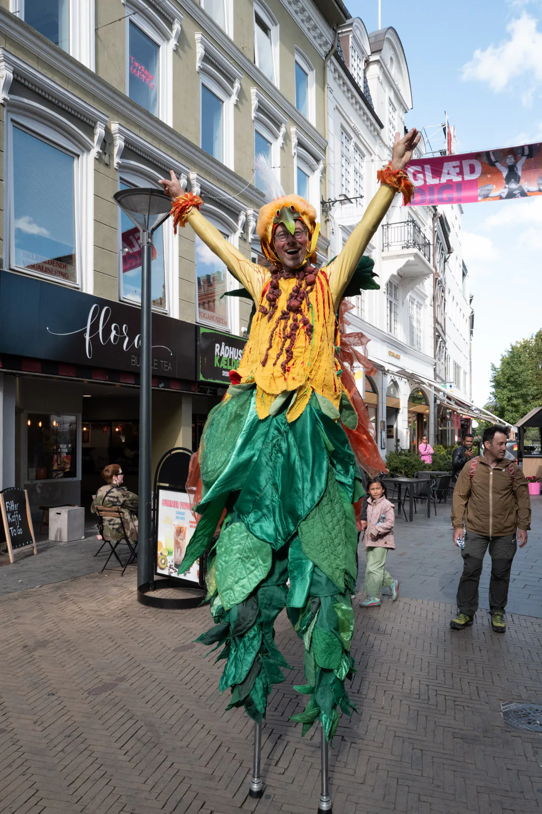 Un échassier costumé en fleur géante, bras levés, Odense
