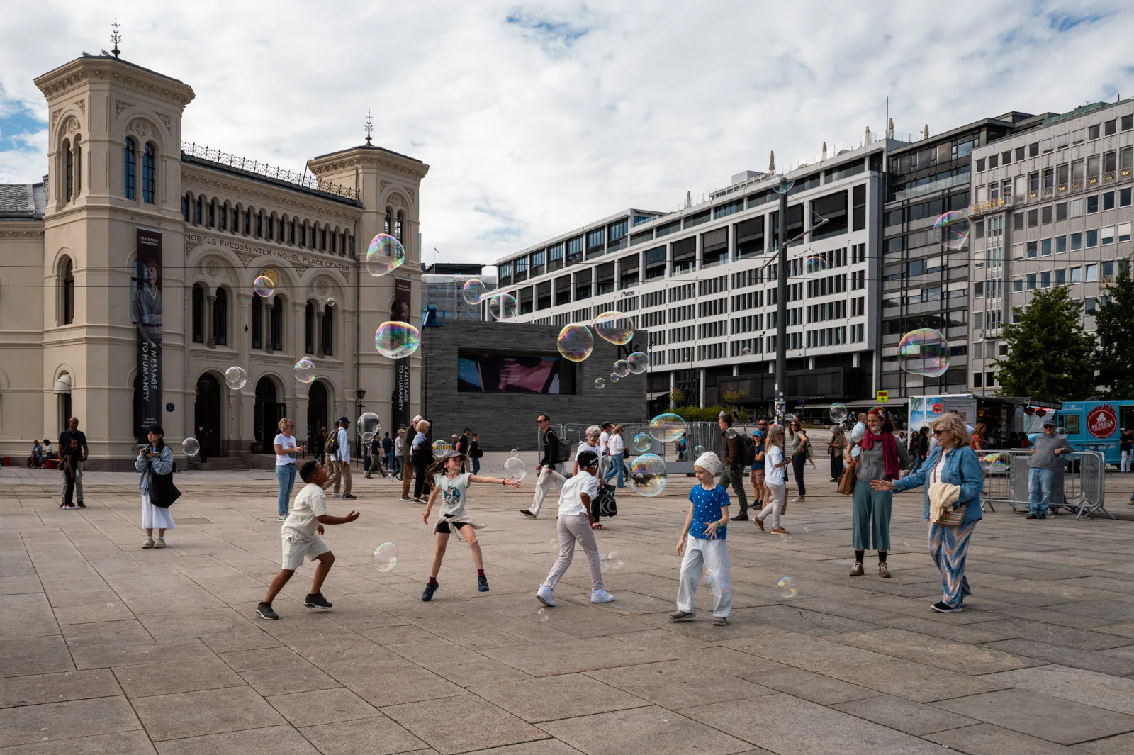 Des enfants courent après les bulles de savon sur une grande place, Oslo
