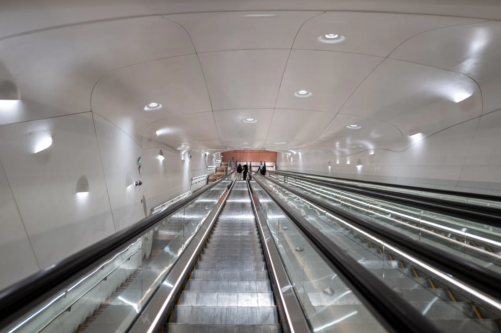 Long escalators under a wavy white ceiling, Paris