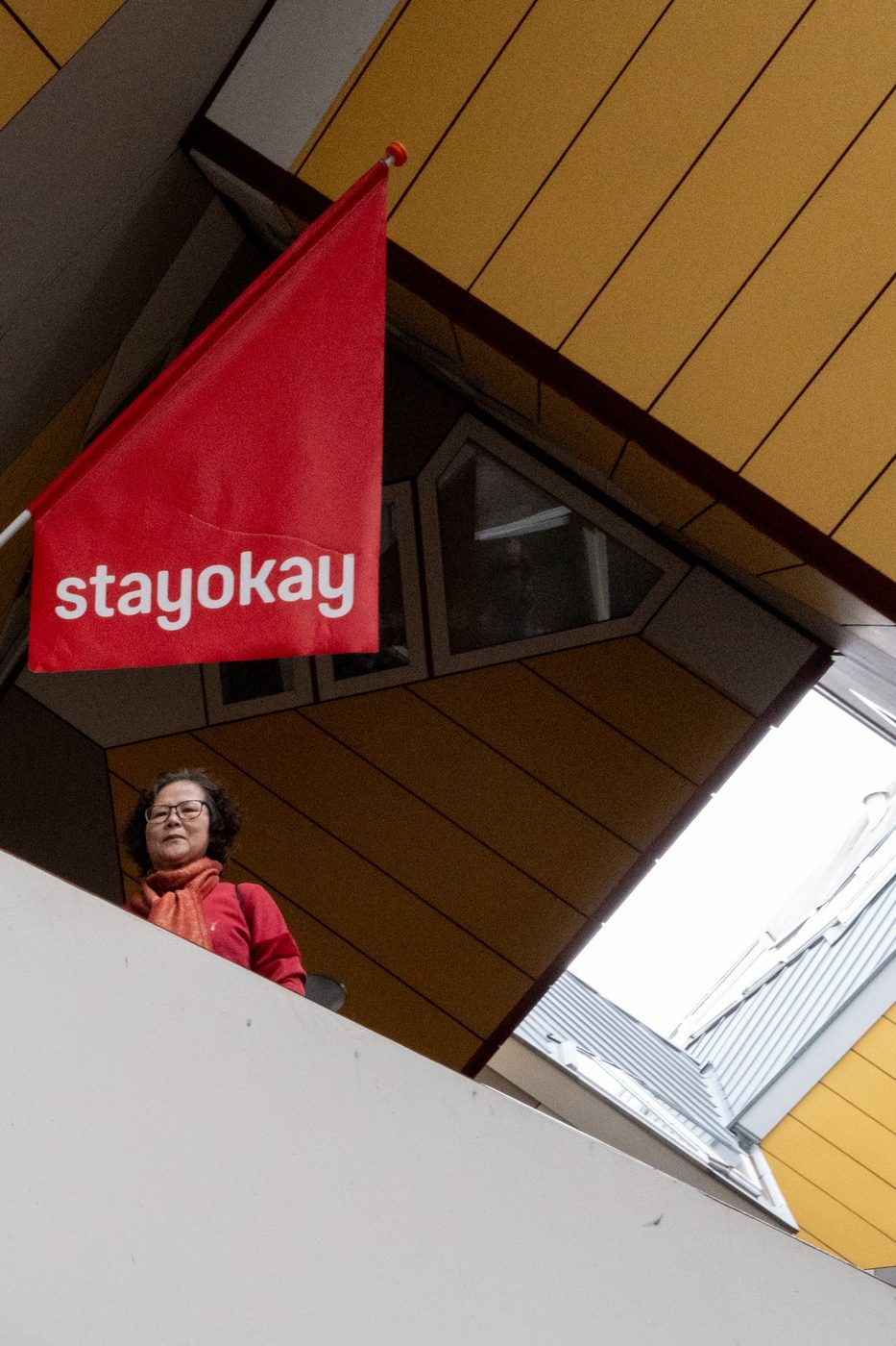 Red Stayokay flag hanging under the yellow awning of a cube house, Rotterdam