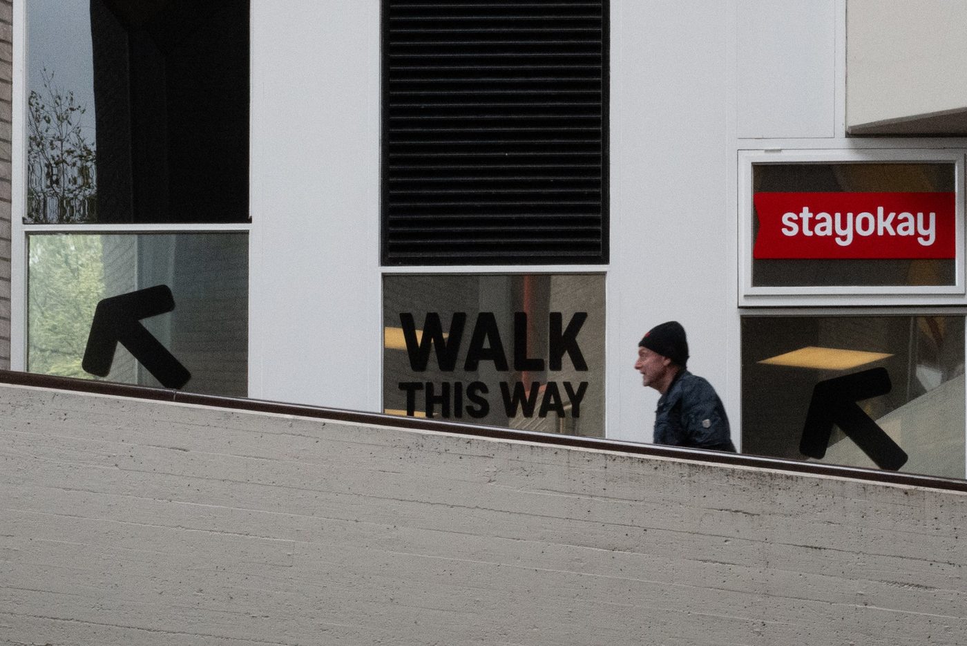 Passer-by walking past a 'walk this way' sign near the hostel, Rotterdam