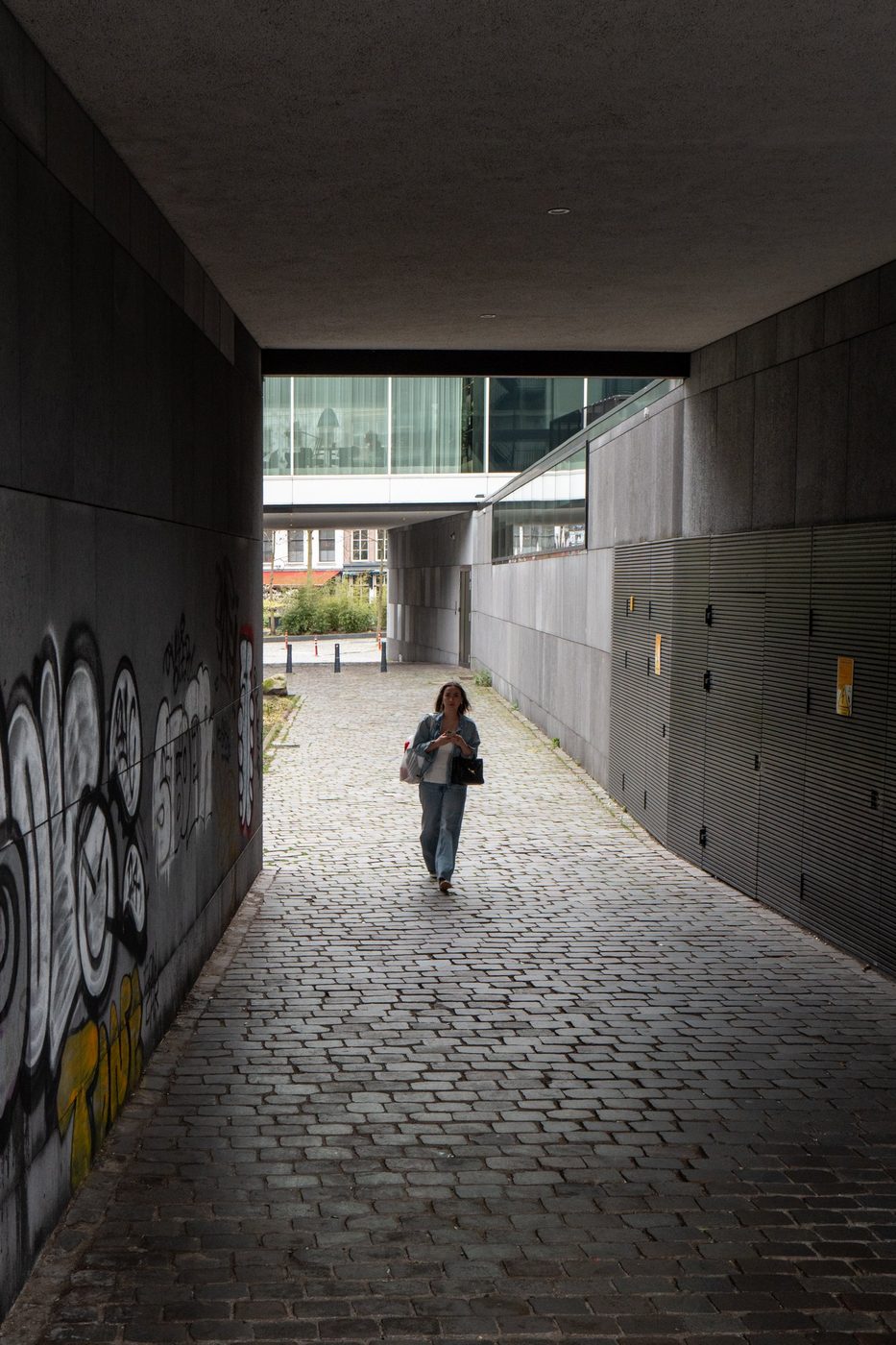 Woman crossing a covered passage tagged with graffiti, Rotterdam