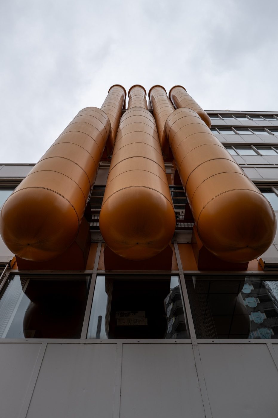 Huge orange tubes on a building facade, seen from below, Rotterdam