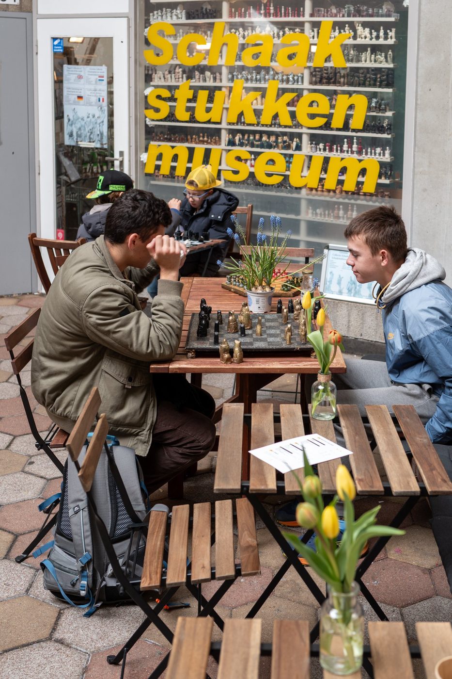 Teenagers playing chess on a terrace in front of a chess piece museum, Rotterdam