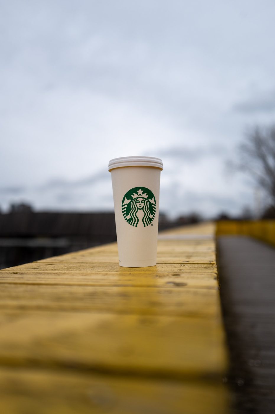 Starbucks cup resting on the yellow railing of the Luchtsingel bridge, Rotterdam