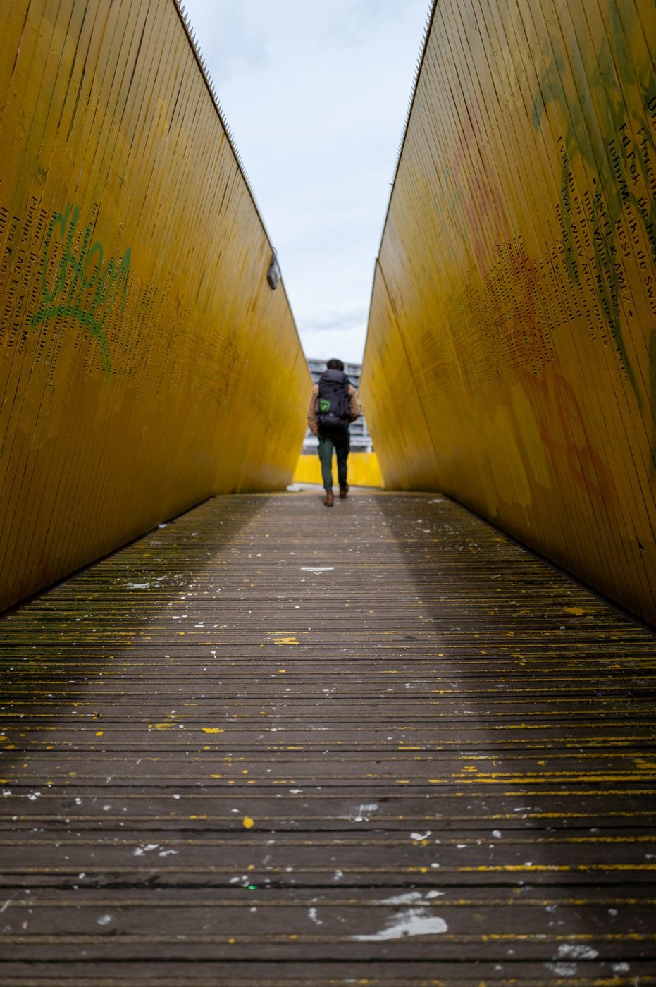 Hiker with a backpack walking away along the yellow walkway, Rotterdam