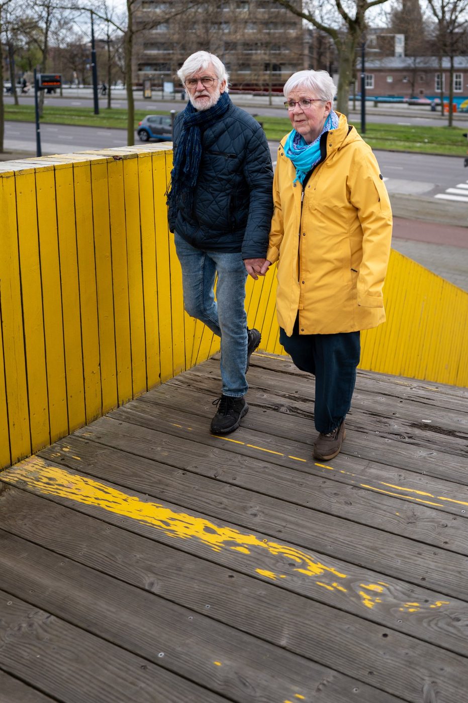 Elderly couple holding hands on the yellow walkway, Rotterdam