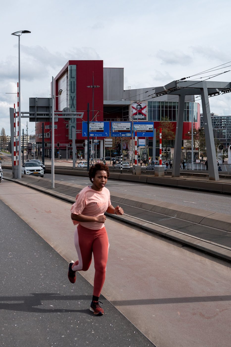 Jogger in pink activewear passing in front of the Luxor Theatre, Rotterdam