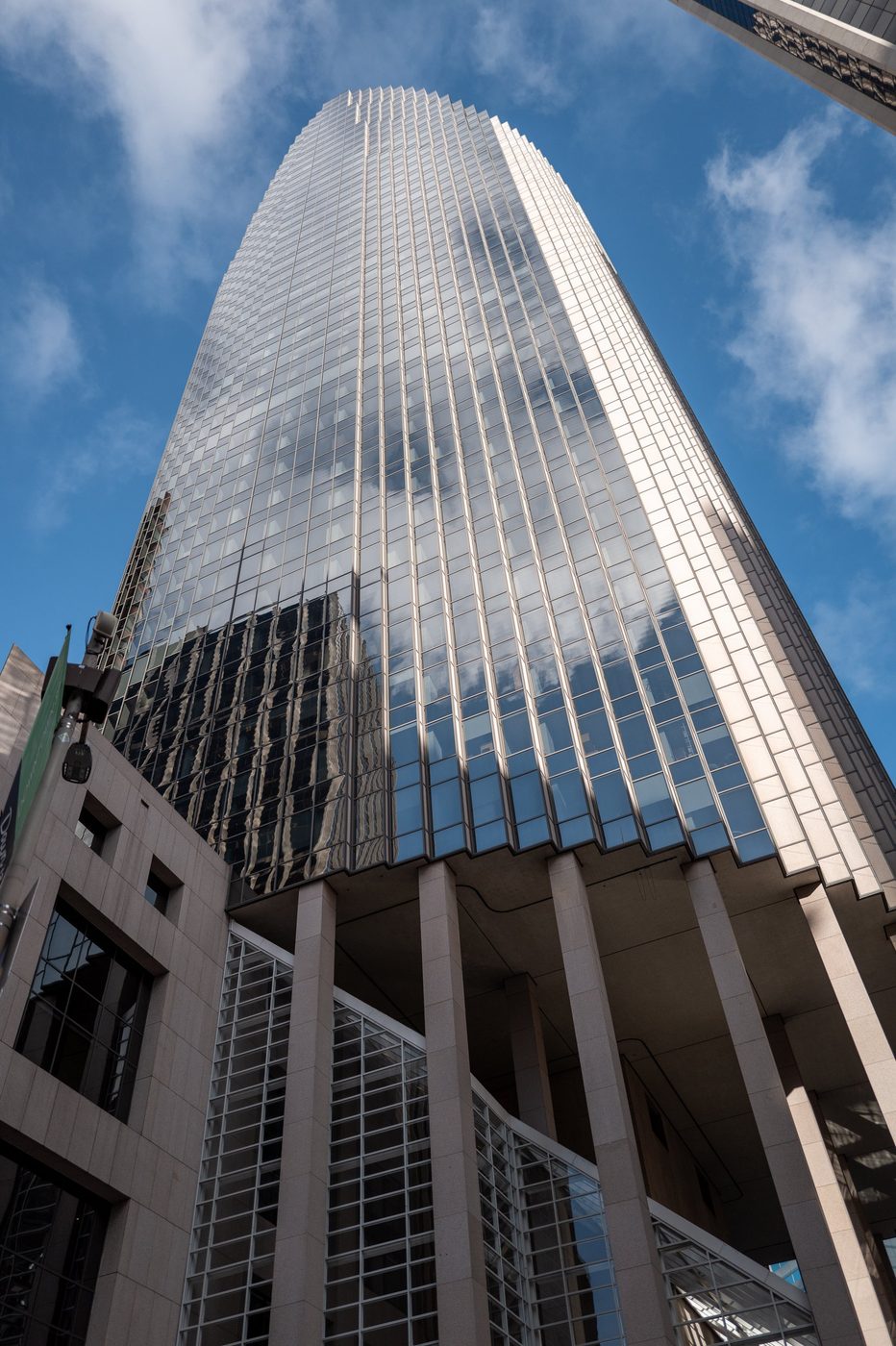 Curved glass skyscraper reflecting the clouds, view looking up from the sidewalk, San Francisco