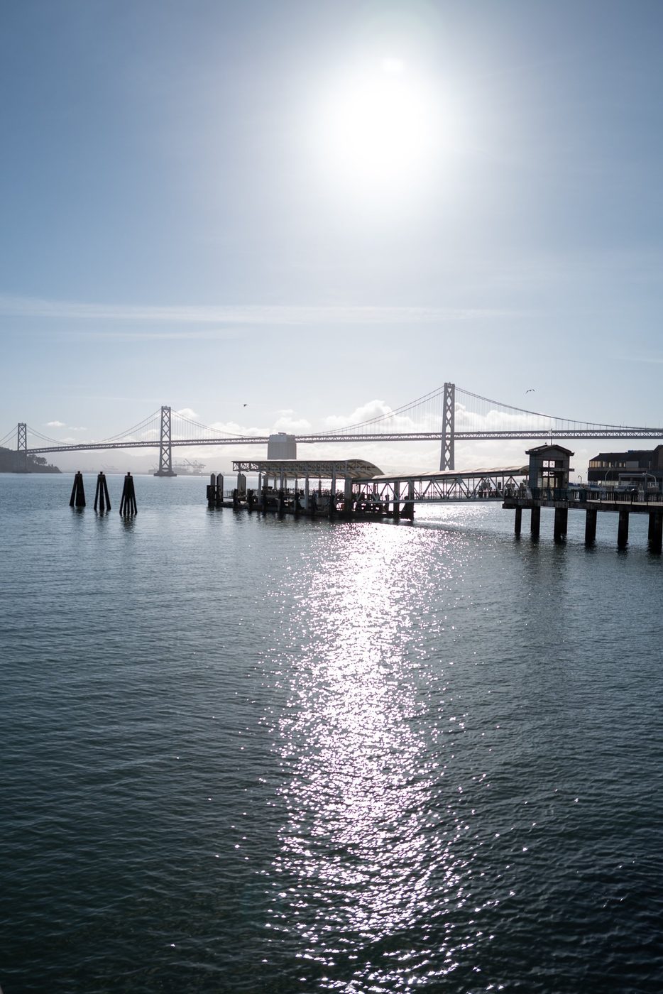 Pier and Bay Bridge backlit, dazzling reflection of the sun on the bay, San Francisco