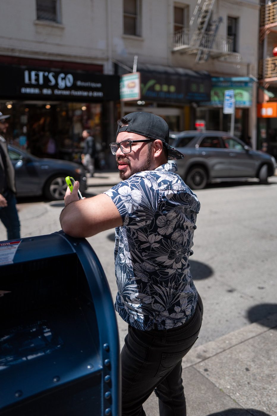 Man in a floral shirt taking a selfie near a blue mailbox, San Francisco