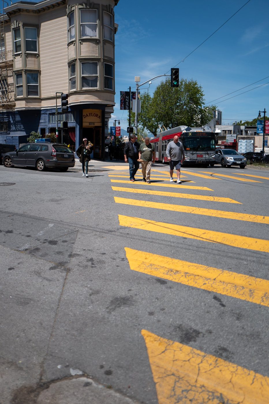 Pedestrians crossing a yellow crosswalk near the Da Flora restaurant, municipal bus at the stop, San Francisco