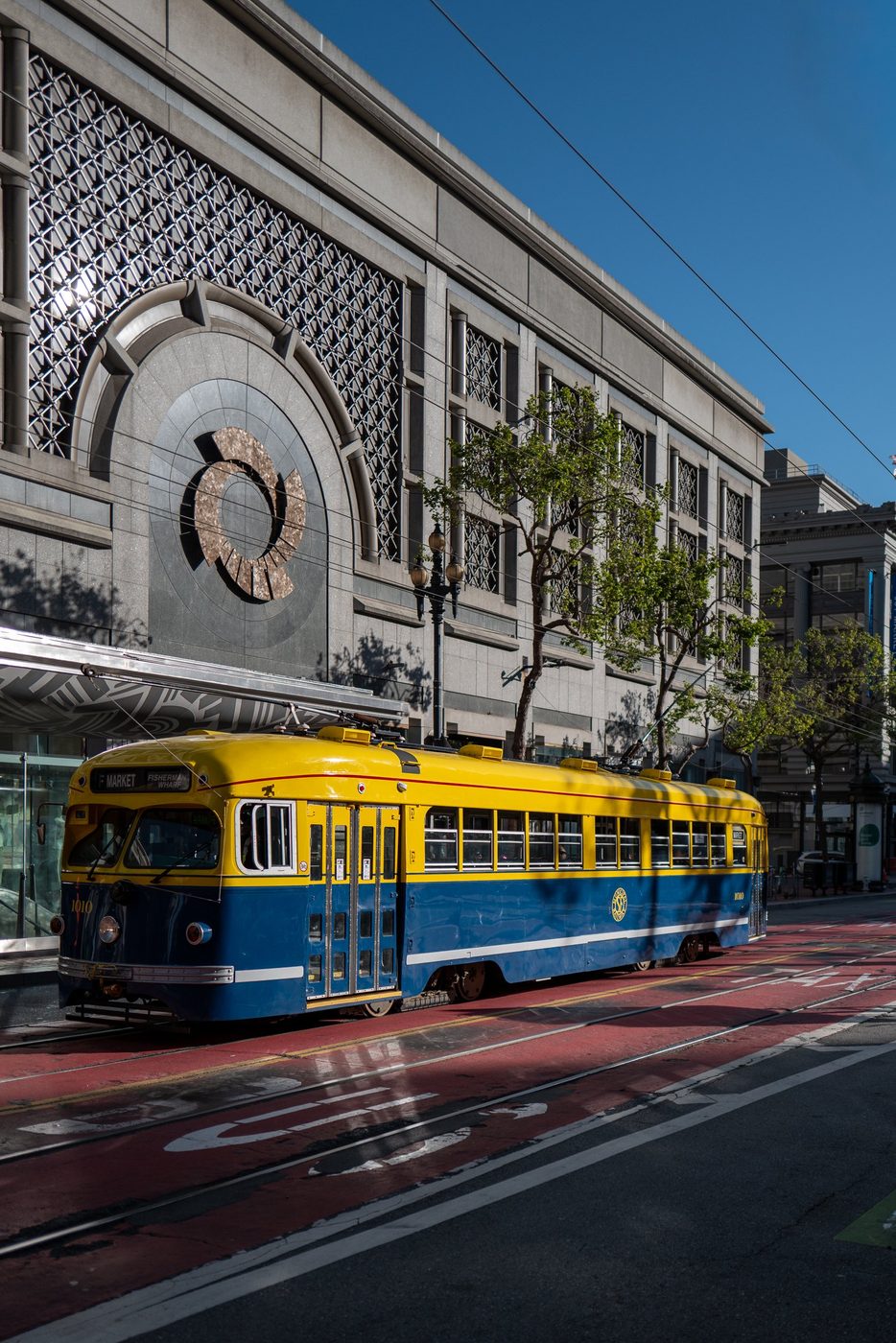 Vintage blue and yellow streetcar number 1010 in front of a façade adorned with a carved circle, San Francisco