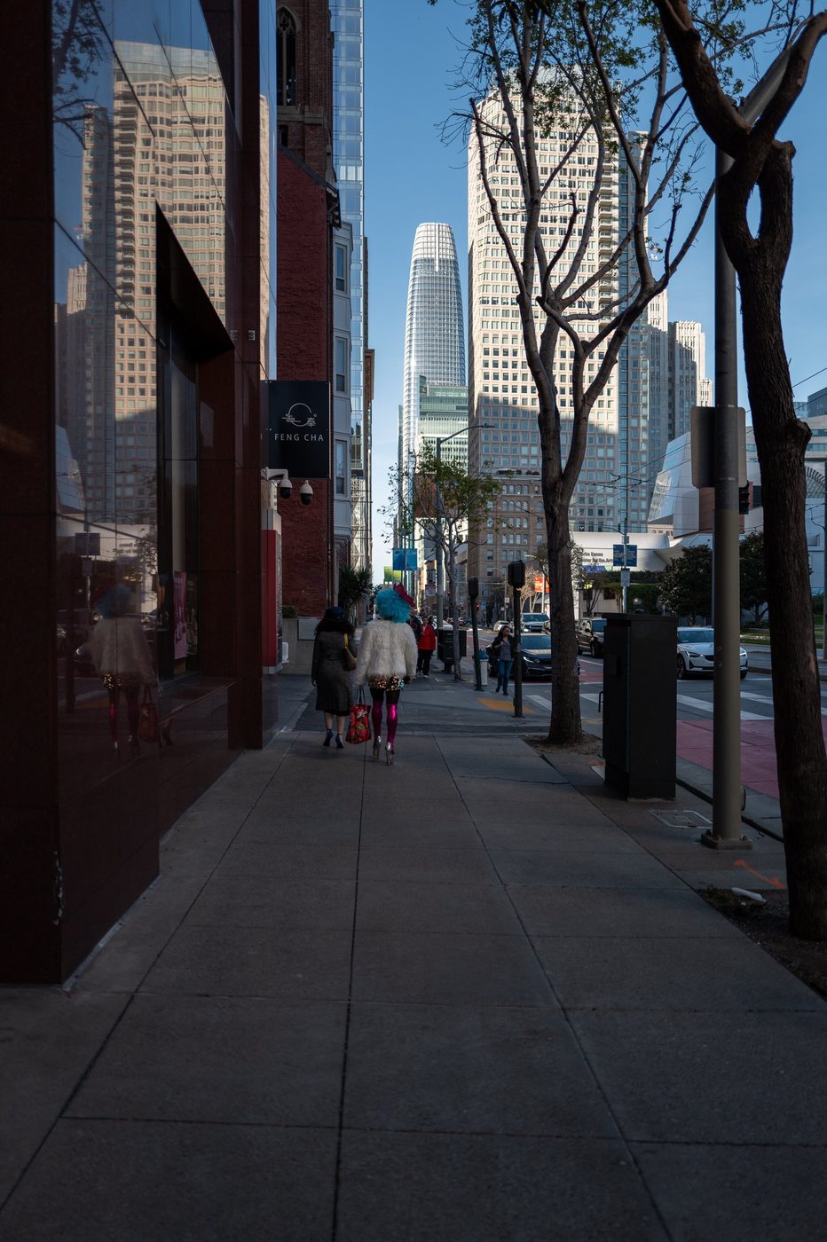 Two passers-by with colorful wigs walking toward Salesforce Tower, San Francisco