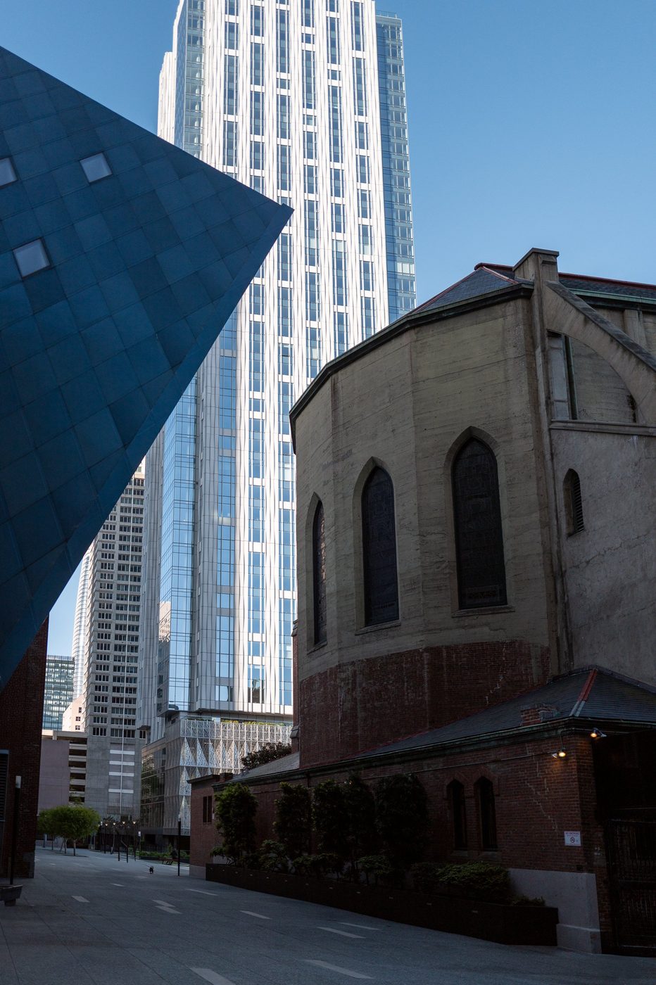 Contrast between a modern glass tower and an old brick church, San Francisco