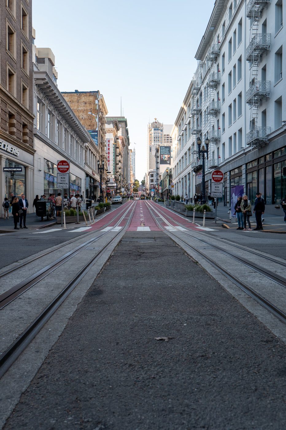 Cable car rails descending a shopping street lined with Do Not Enter signs, San Francisco