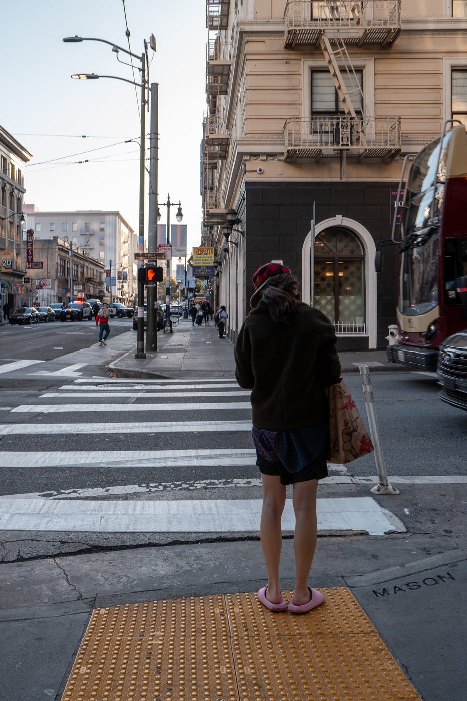Passer-by in pink slippers waiting to cross near a double-decker bus, San Francisco