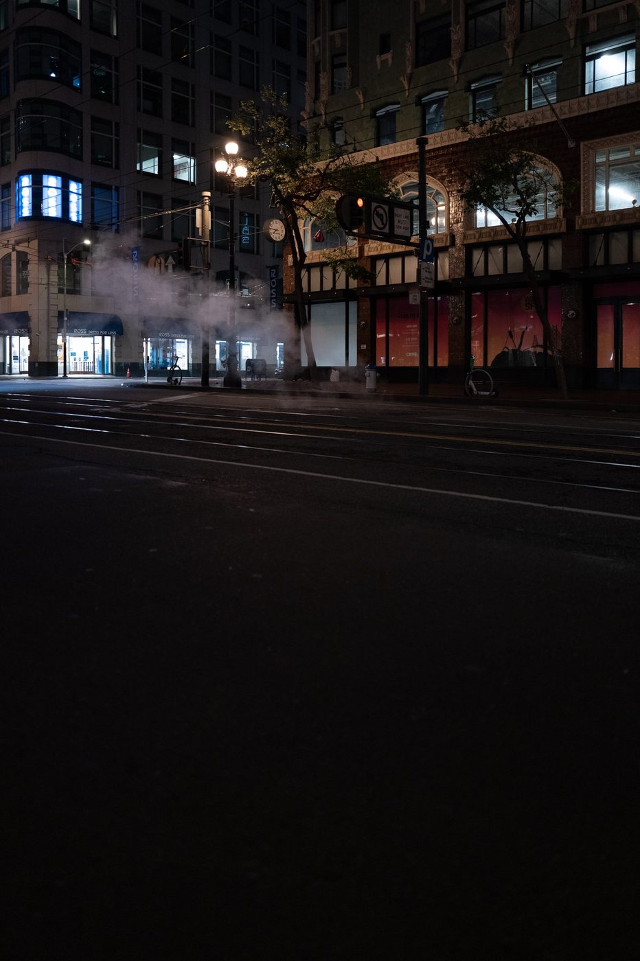 Night steam escaping from the ground near the lit windows of the Ross store, San Francisco