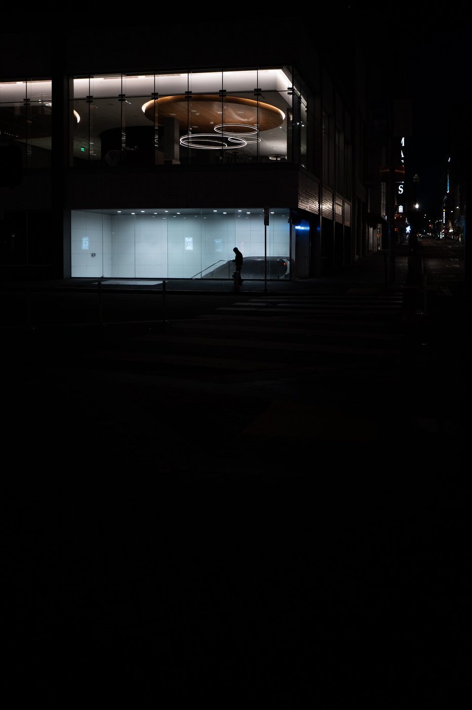 Lone silhouette in the glazed lobby of a building lit up at night, San Francisco
