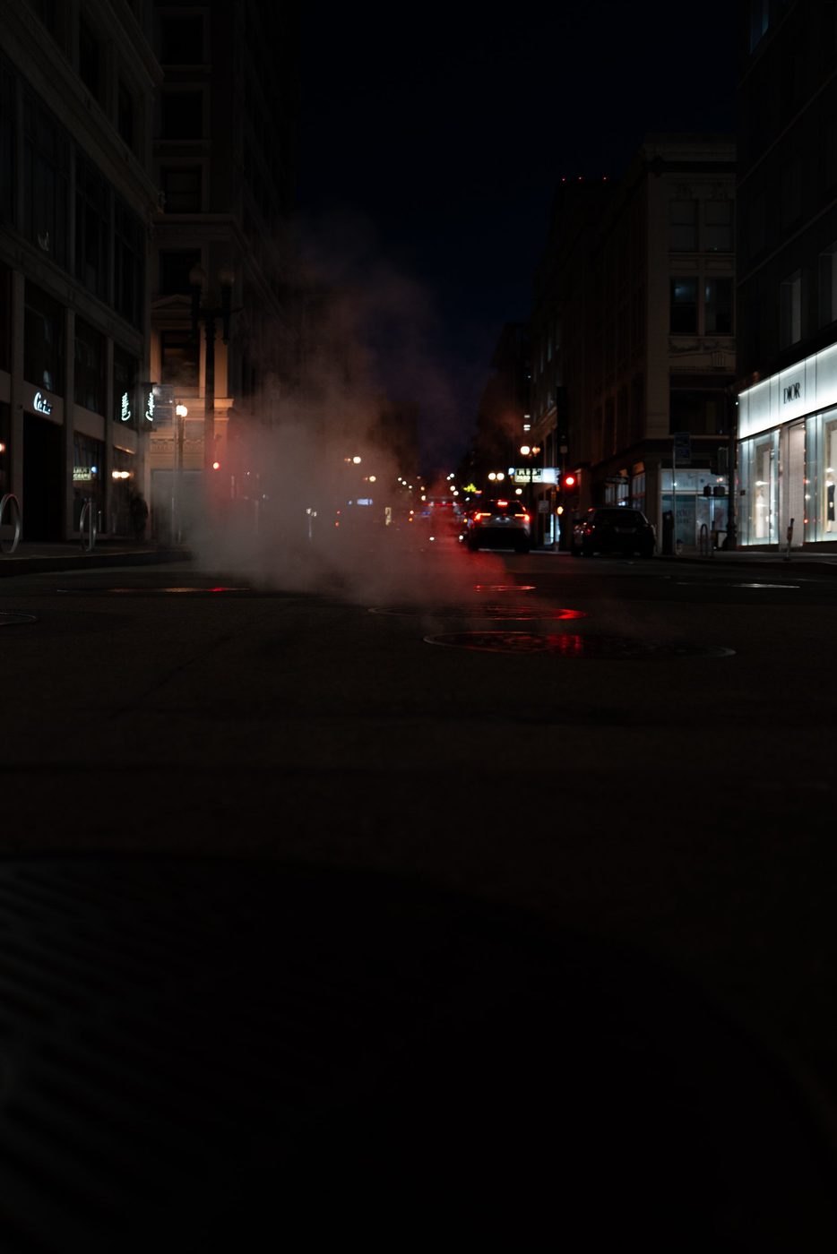 Red taillights disappearing into the steam of a night street, illuminated Dior storefront, San Francisco