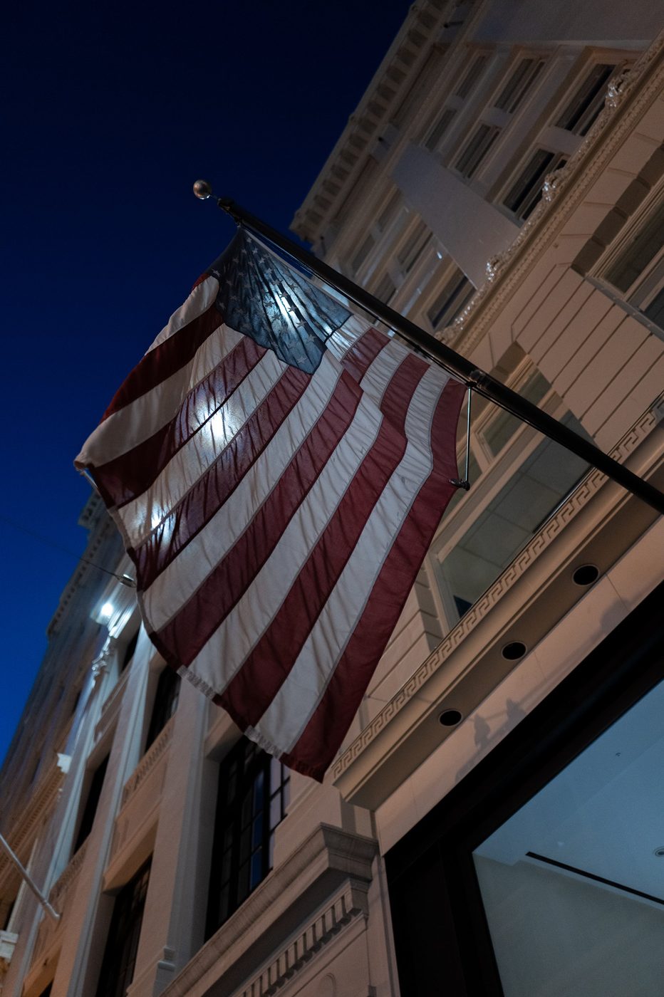 Illuminated American flag flying in front of a classic façade at night, San Francisco