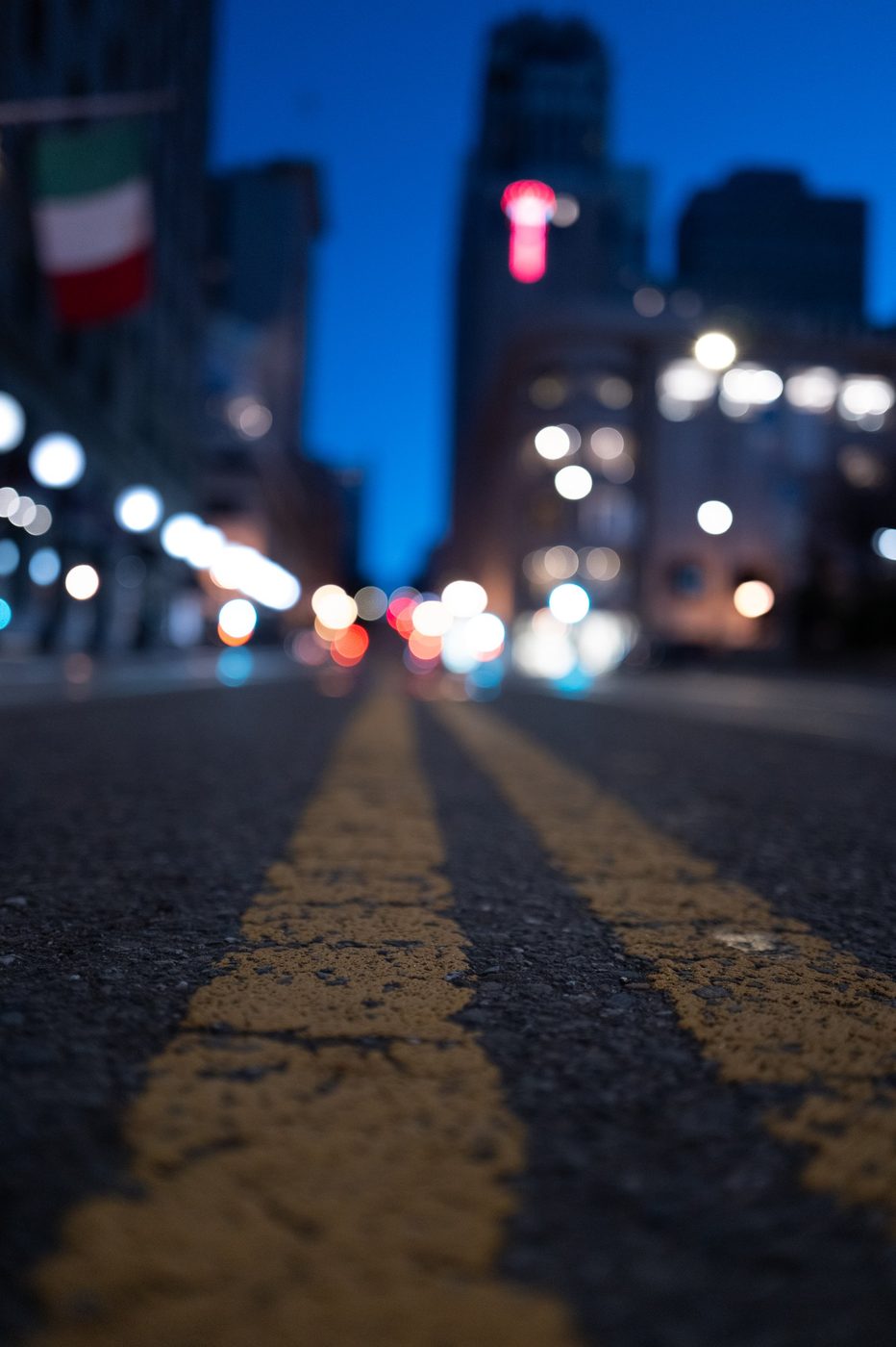 Yellow road line in the foreground, blurred city lights at night, San Francisco