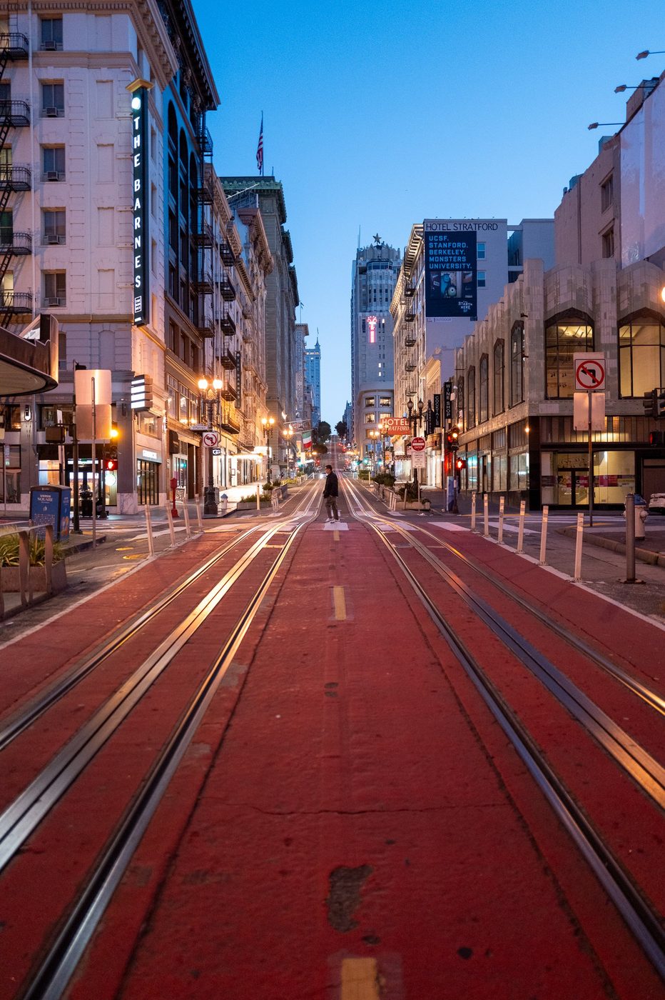 Pedestrian crossing the red rails of California Street at nightfall, San Francisco
