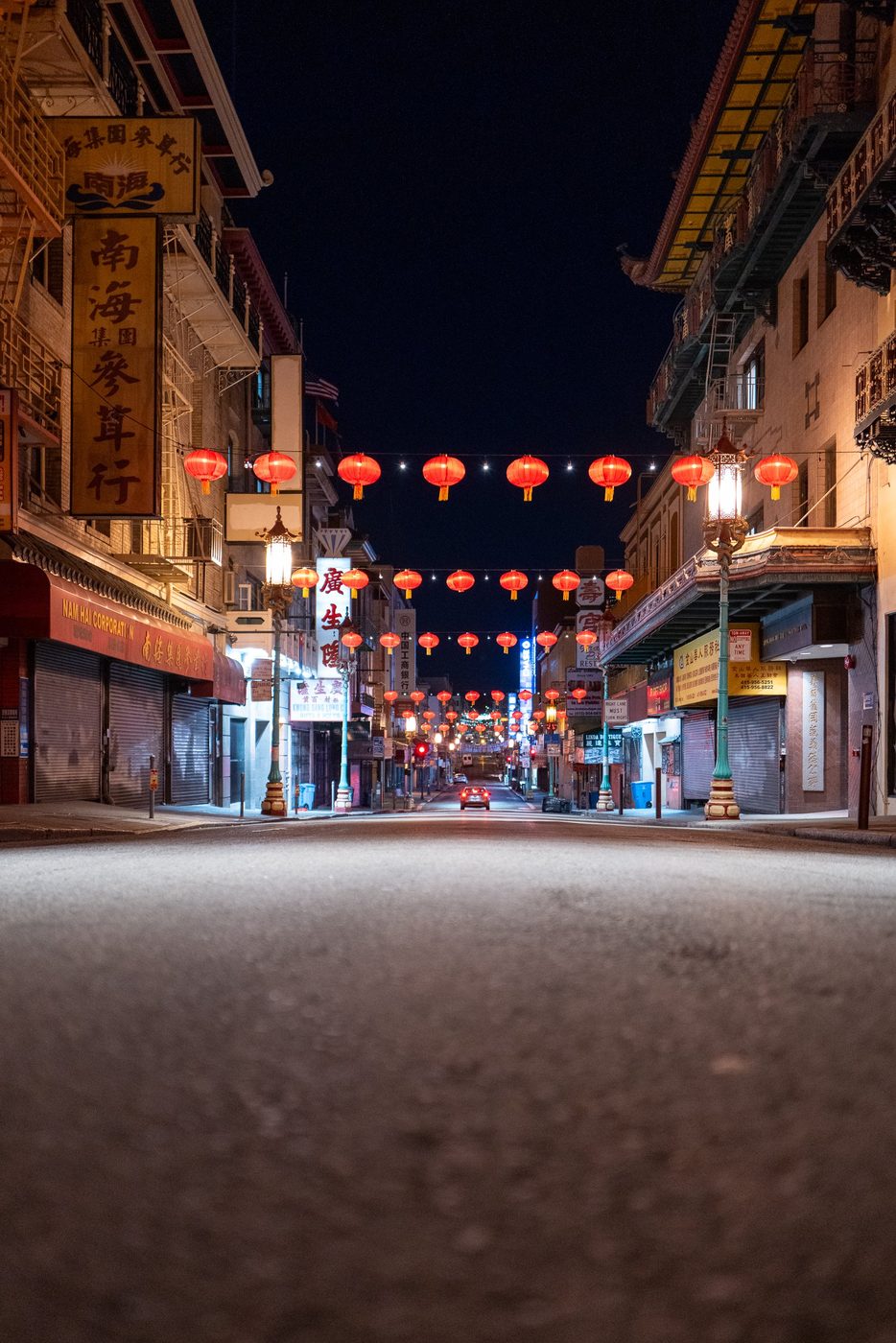 Car approaching under the red lanterns of a Chinatown street at night, San Francisco