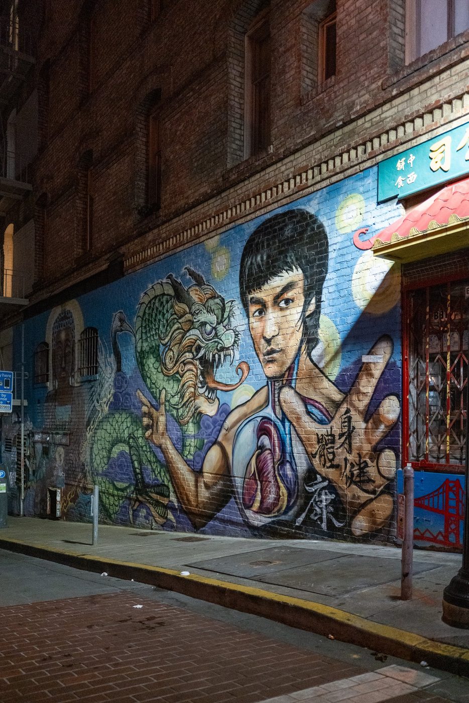 Mural of Bruce Lee and a green dragon, storefront of a Chinatown restaurant at night, San Francisco