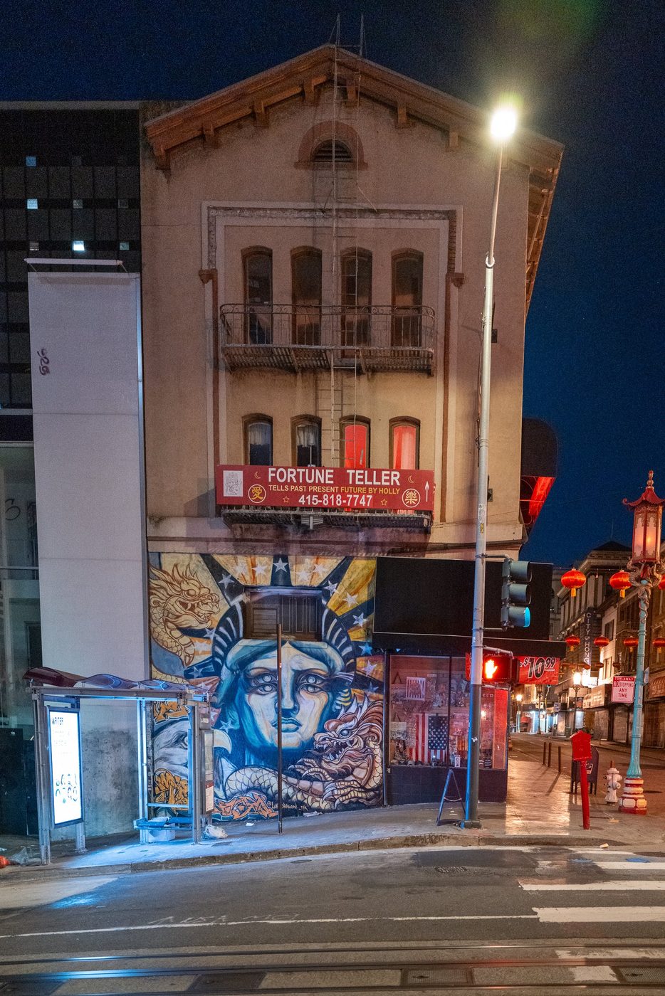 Mural of a stylized Statue of Liberty on the façade of the Fortune Teller building at night, San Francisco