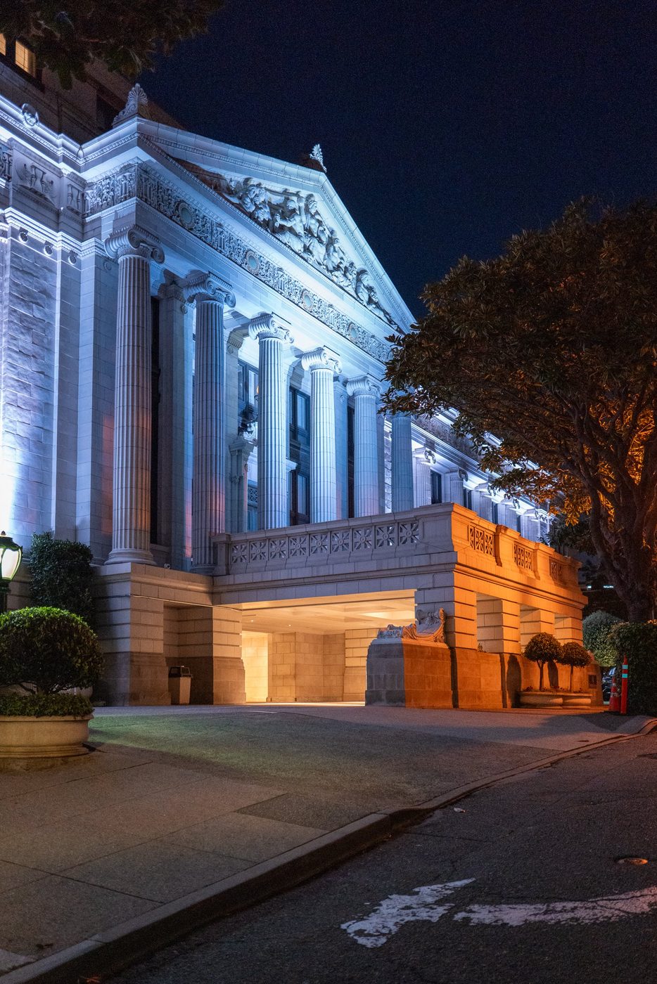 Neoclassical colonnade lit in blue and gold at the entrance of a building, San Francisco