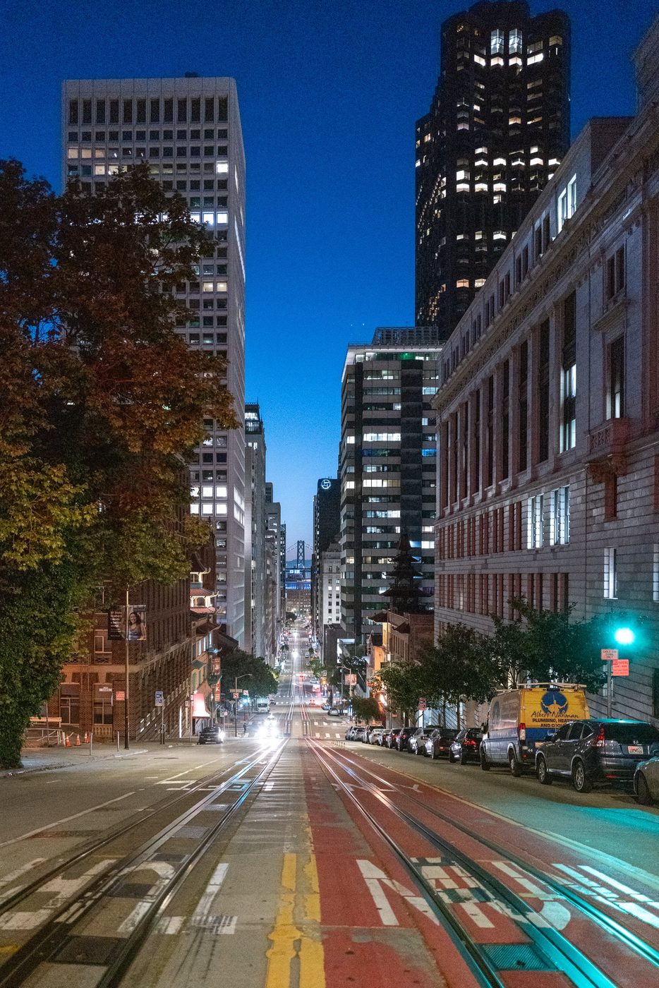 Night view of a sloping avenue lined with lit office towers, San Francisco