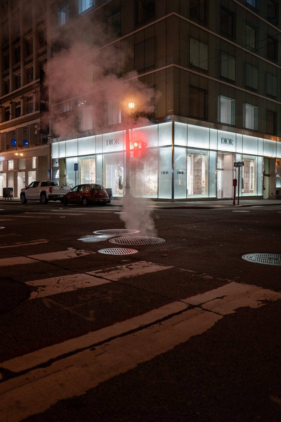 Night steam rising in front of the glazed corner of the Dior boutique, red light on, San Francisco