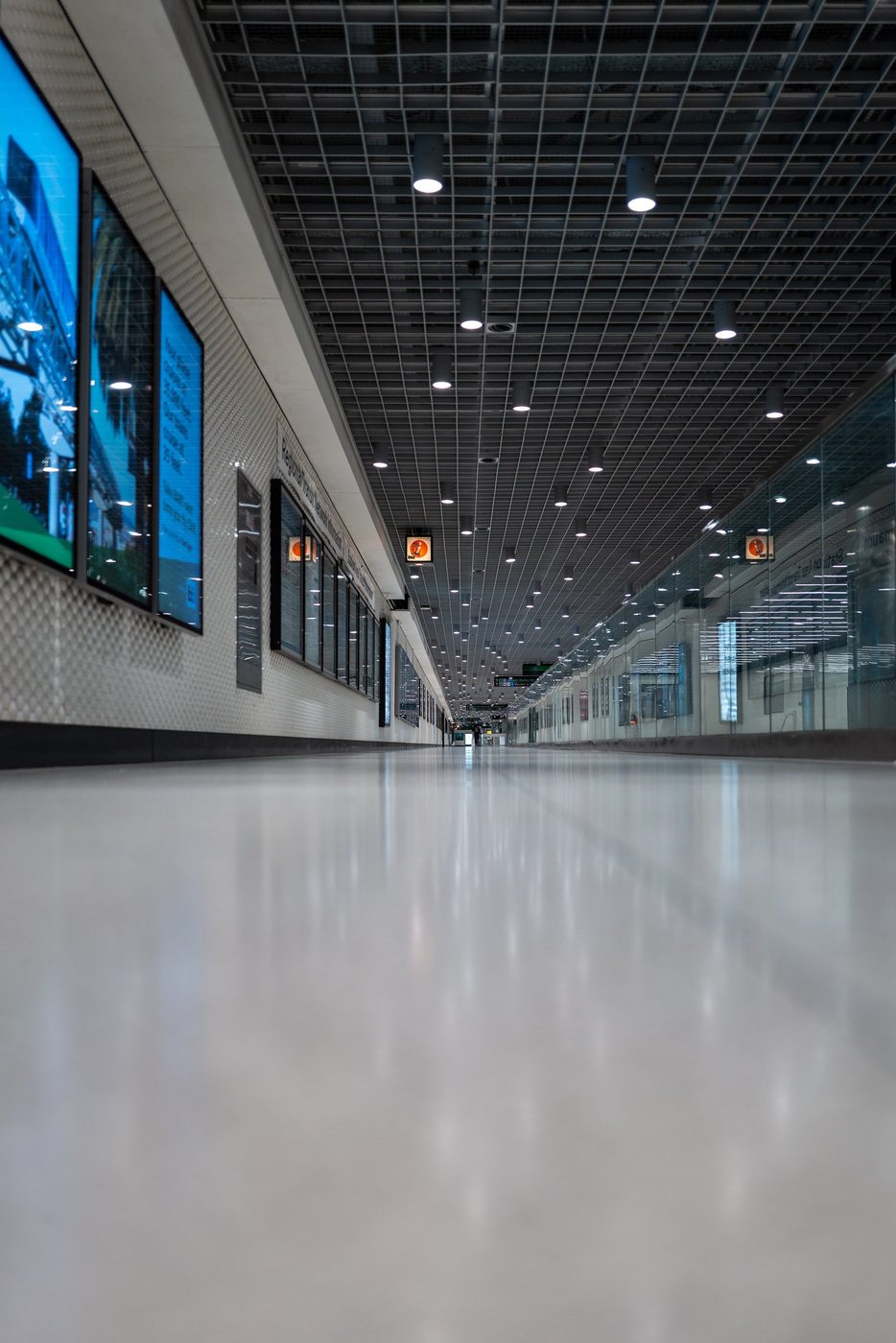 Long underground corridor with a metal coffered ceiling, advertising screens on the side, San Francisco