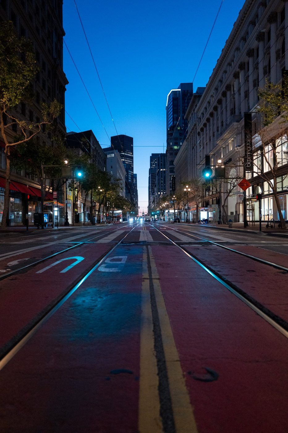 Red bus lane marked with a U-turn, shopping street at dusk, San Francisco