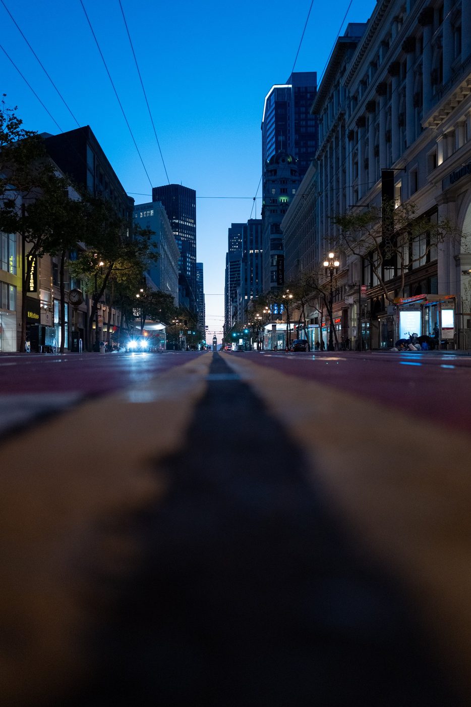 Sloping street at dusk lined with buildings, Hotel Zelos sign in the distance, San Francisco