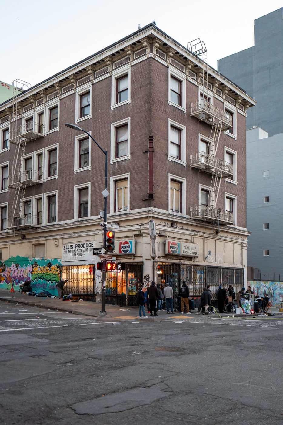 Brick corner building with the Ellis Produce and Pepsi signs, small group on the sidewalk, San Francisco