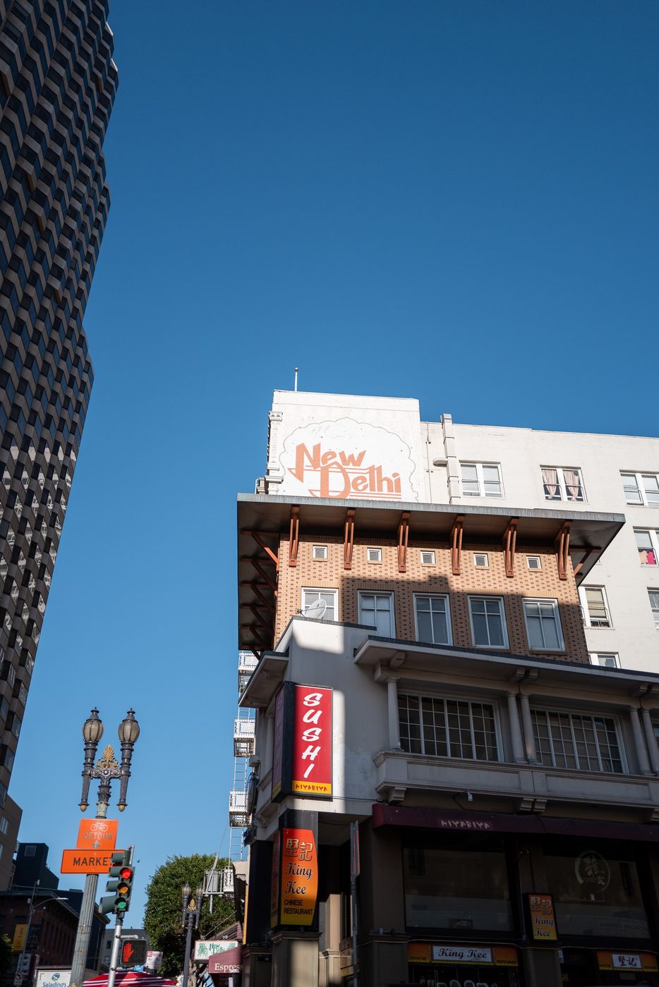 Painted New Delhi sign atop a building, Sushi and King Kee restaurants below, San Francisco