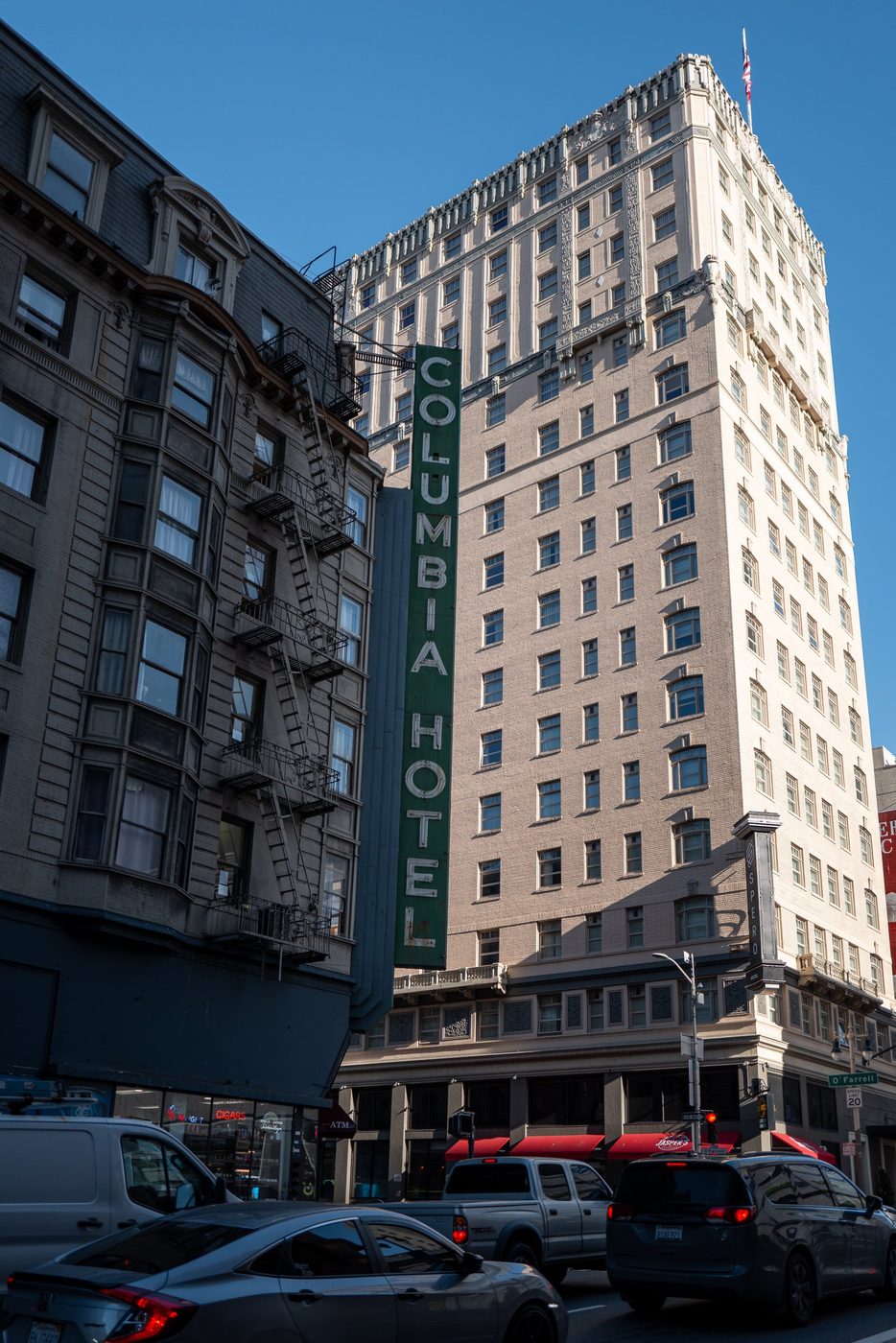 Green vertical Columbia Hotel sign against the façade of an old building, San Francisco