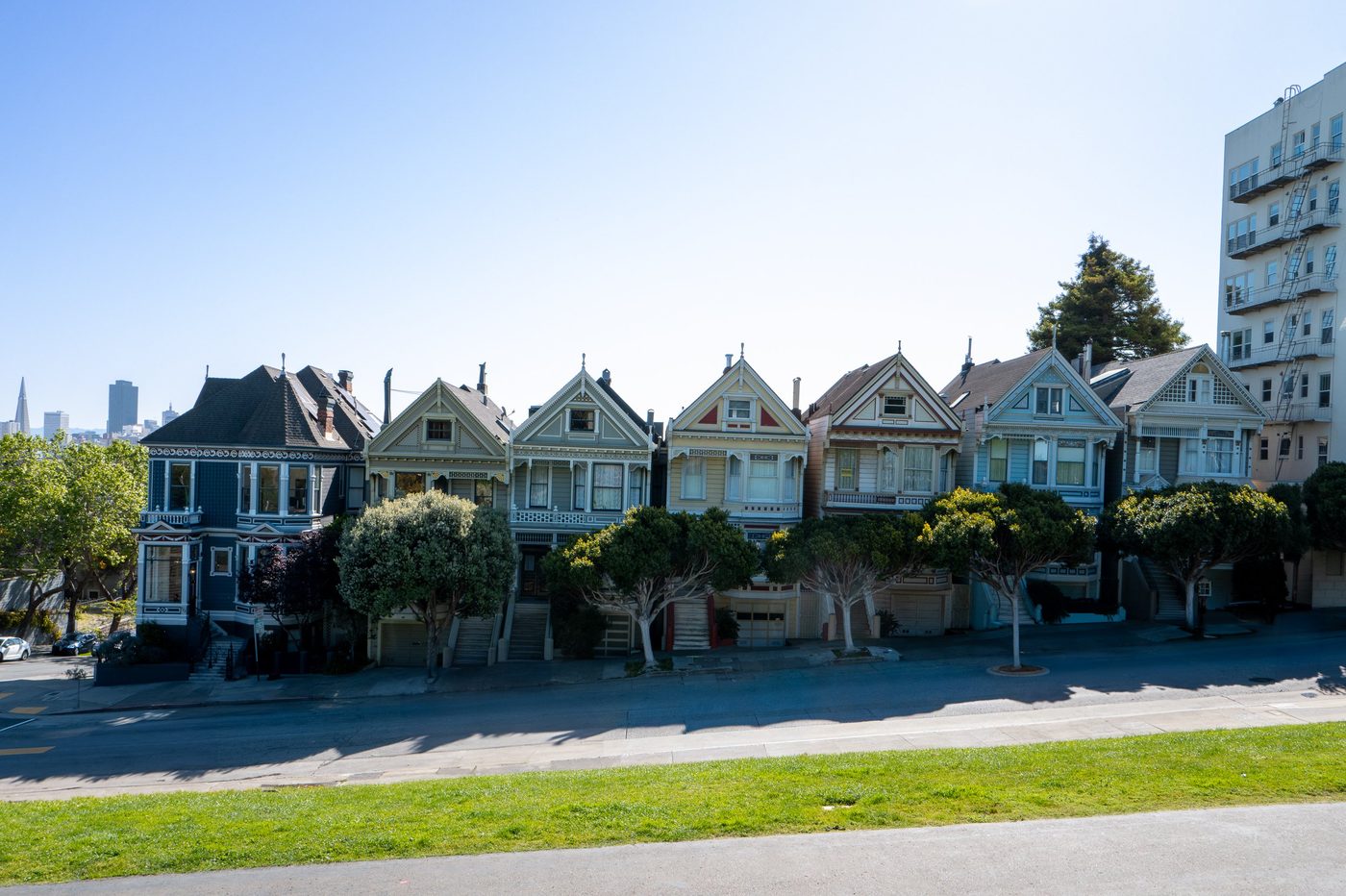 Row of colorful Victorian houses facing the park, city silhouette in the distance, San Francisco