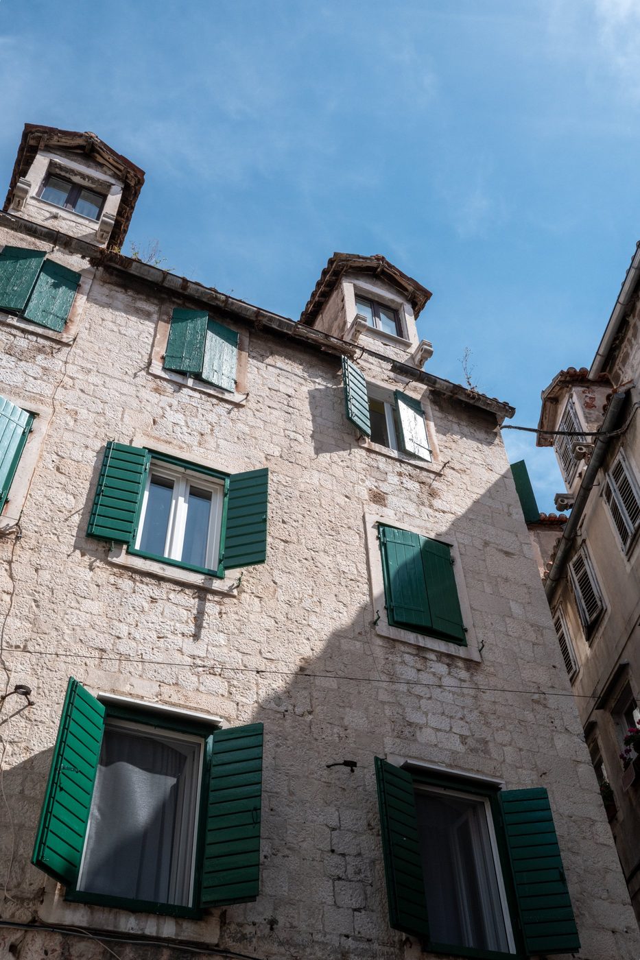Light stone facade with green shutters and multi-story windows, Split