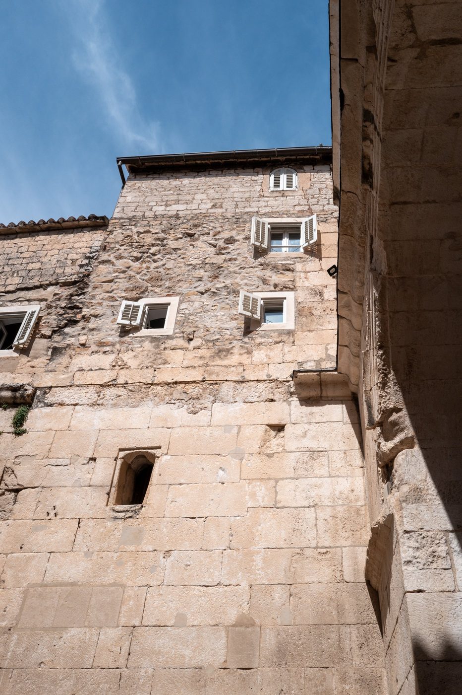 Stone wall with white-shuttered windows seen from below, Split
