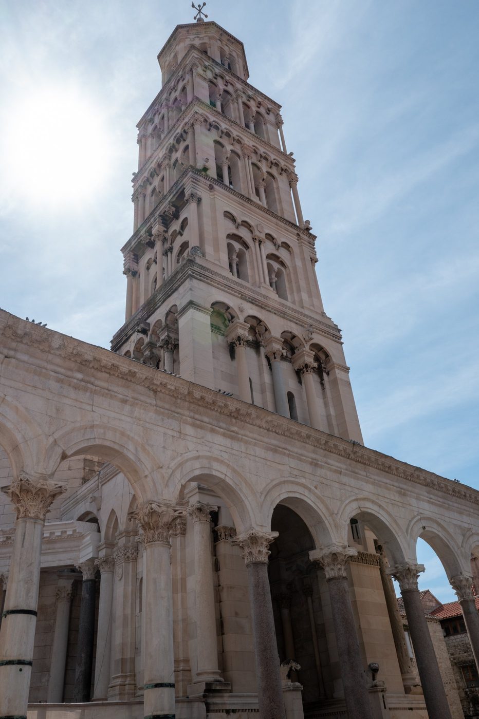 Bell tower with stacked Romanesque arcades under a clear sky, Split