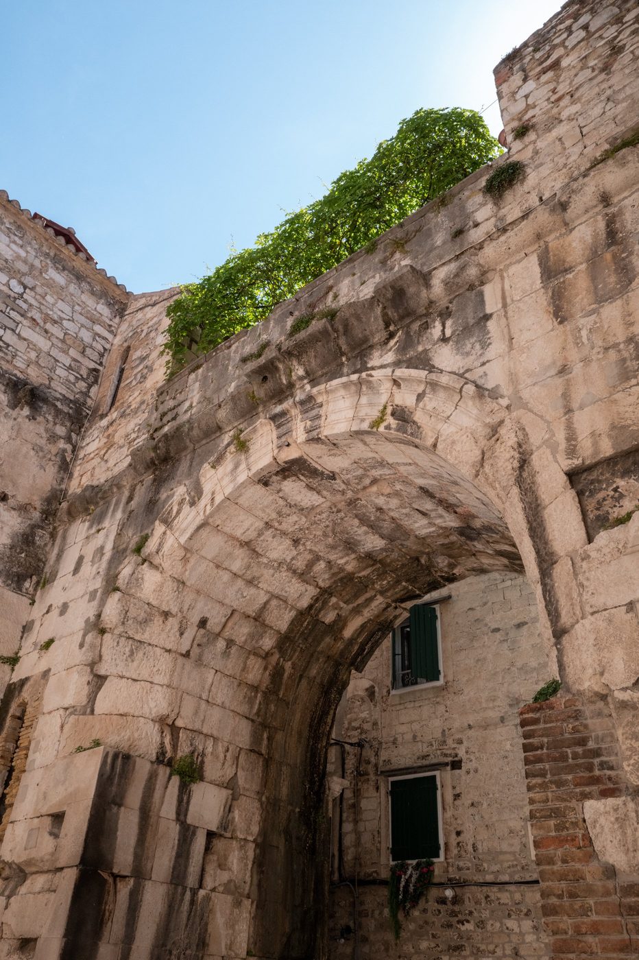 Stone arch overgrown with ivy above an alley, Split