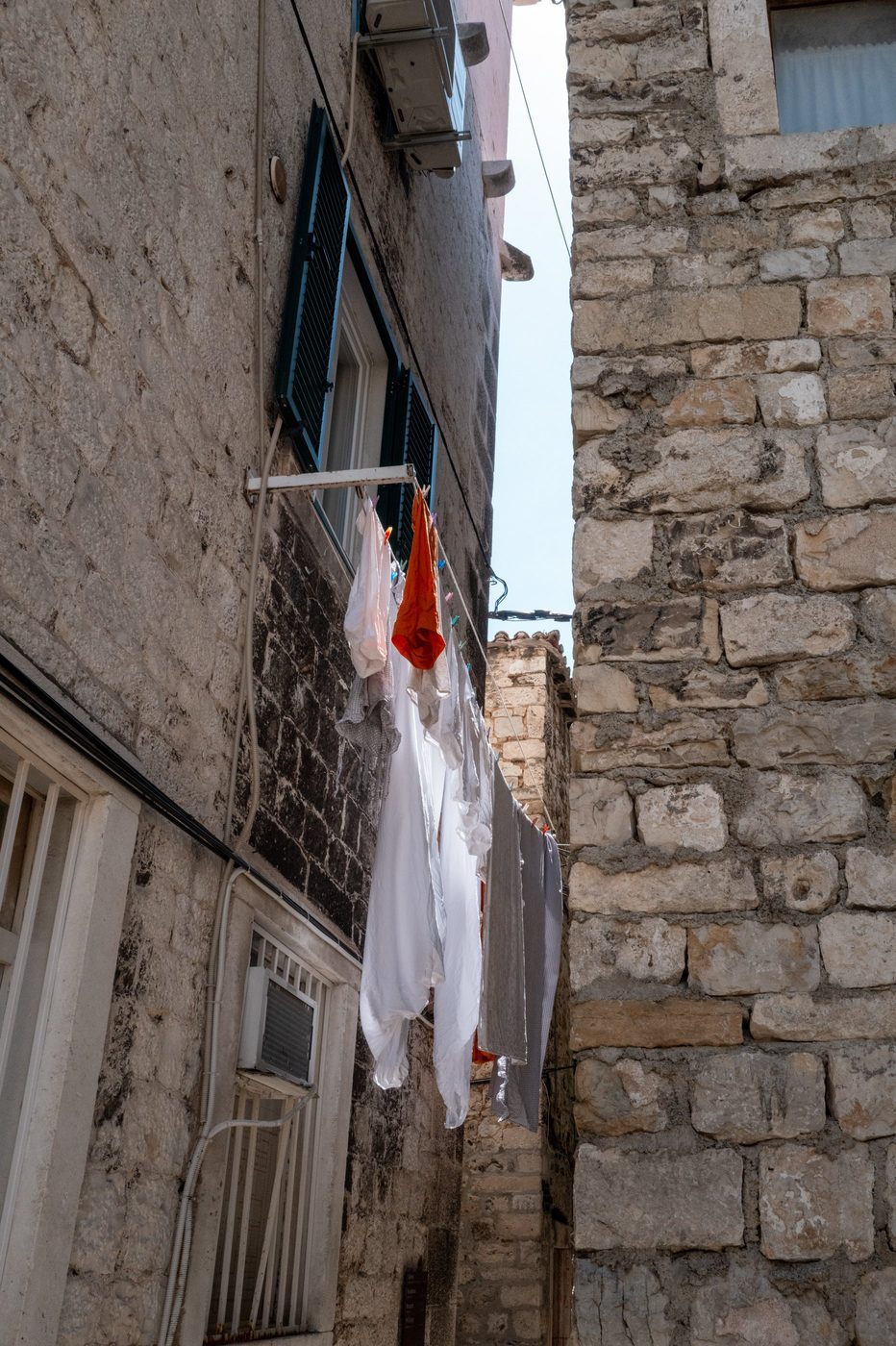 White laundry hung between two stone facades, Split