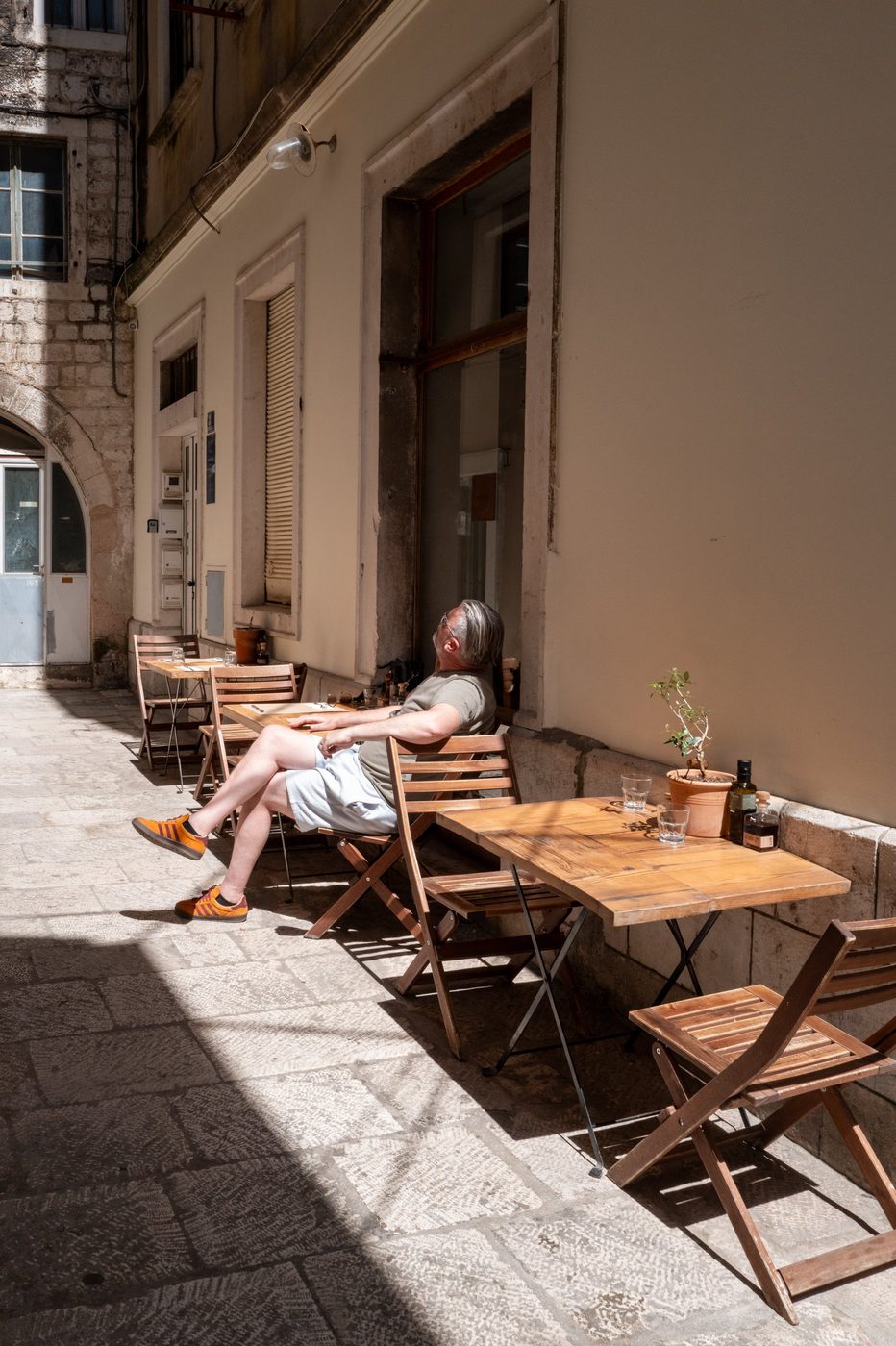 Relaxed customer at a caf&eacute; table in full sunlight, Split